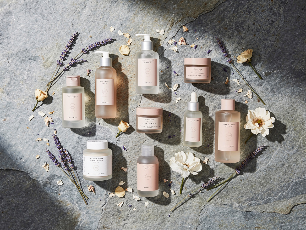 Professional flat lay product photography of artisanal skincare bottles on a stone surface with dried flowers